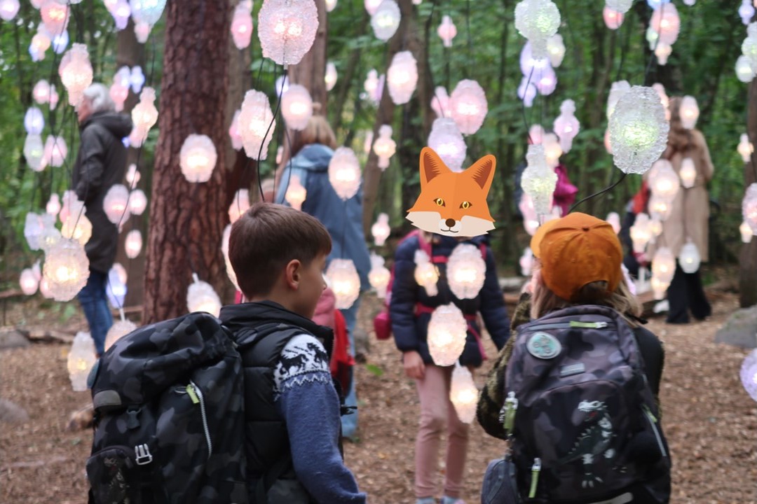 en gruppe mennesker som går gjennom en park med en tegneseriefigur