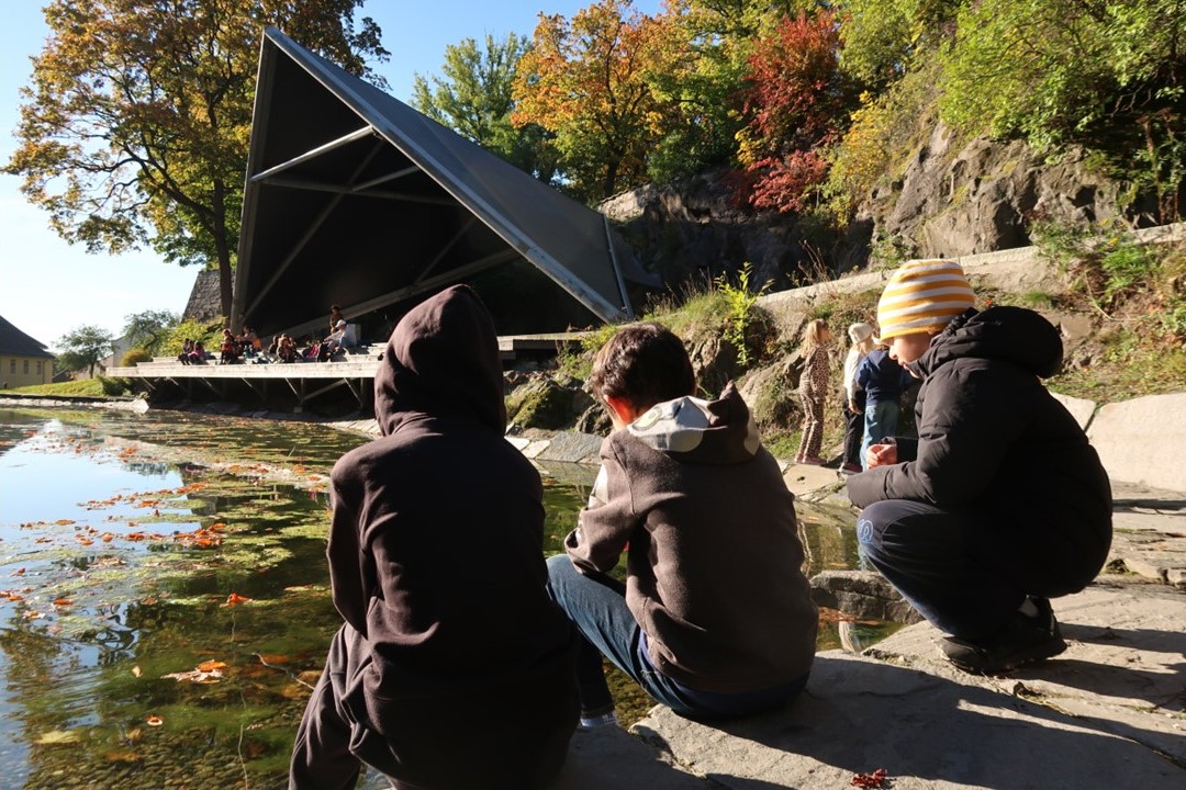 en gruppe mennesker som sitter på en stein ved en innsjø