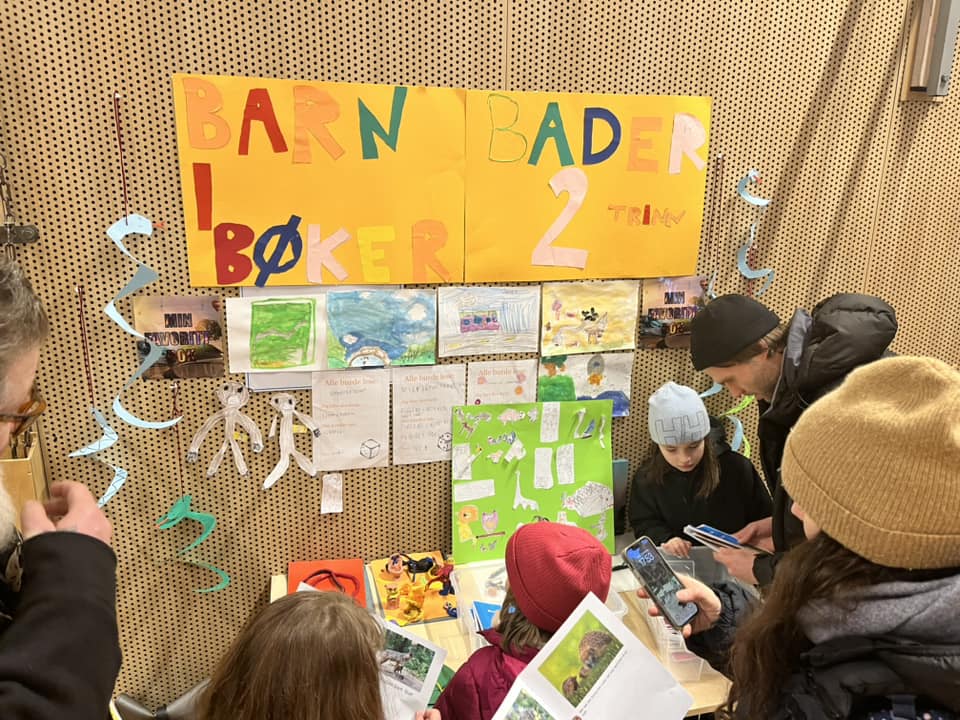En gruppe mennesker som sitter ved et bord med plakater på veggen