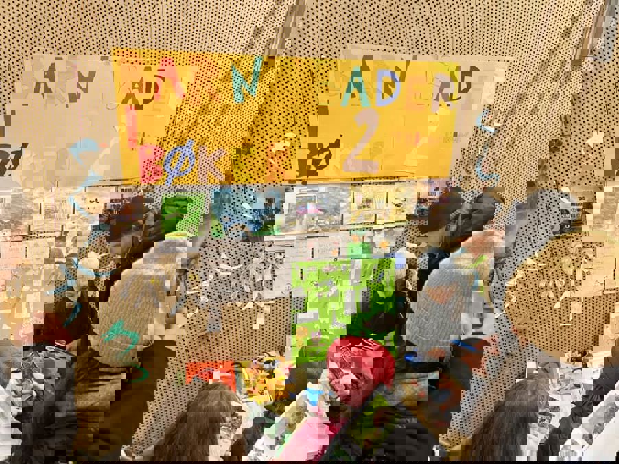 En gruppe mennesker som sitter ved et bord med plakater på veggen